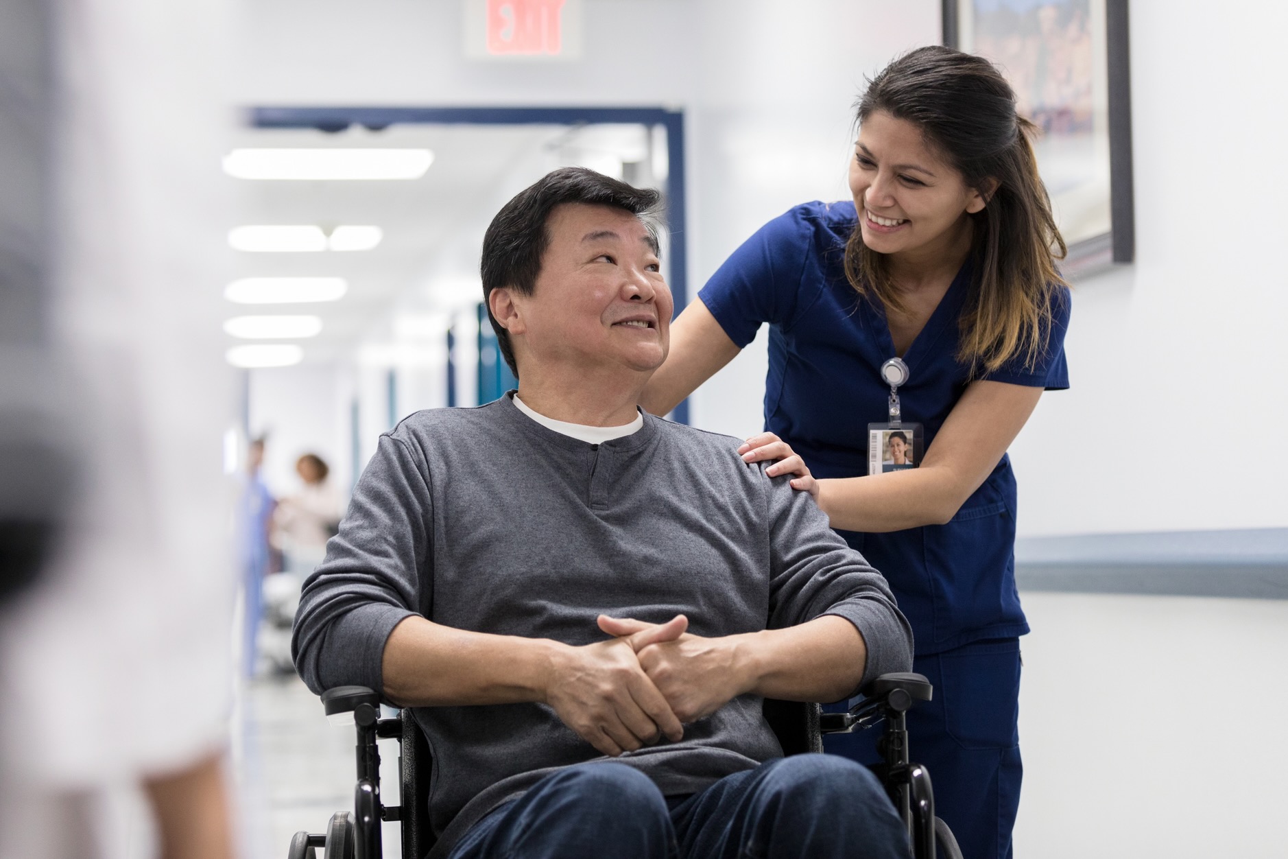 Health services assistant wheels adult man in wheelchair